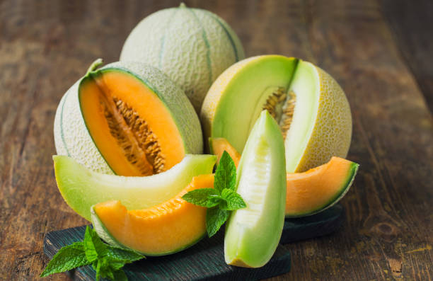 fresh ripe melons on the wooden table - melon imagens e fotografias de stock