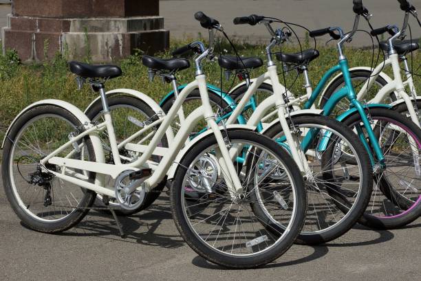 a row of white and blue bicycles parked a row of white and blue bicycles parked in the street on gray asphalt rent a bike stock pictures, royalty-free photos & images