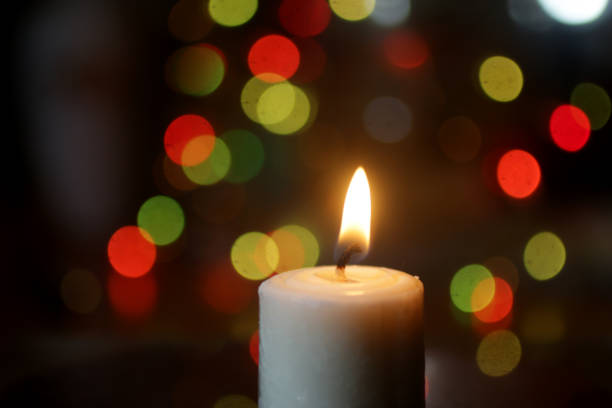 istock White candle light in the night on colorful bokeh light background. 1291612651
