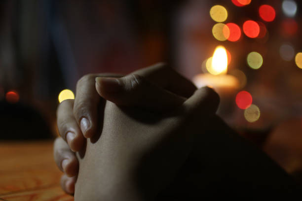 une jeune fille priant dans la nuit sur le fond flou de la lumière blanche de bougie et des lumières de bokeh de noël. - evening prayer photos et images de collection