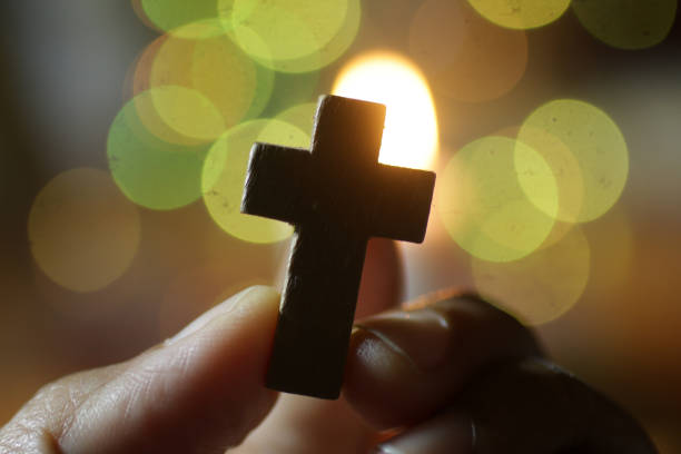 crucifijo de la santa cruz de madera en la mano en el bokeh de oro brillante horneado ligero. - praying human hand worshipper wood fotografías e im�ágenes de stock