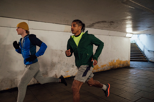 Side view of male friends running together through an underground subway getting fit during lockdown. They are in Newcastle Upon Tyne.