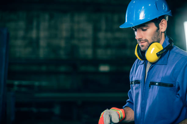 kaukasischer ingenieur arbeiter trägt safty blauhelm und uniform mit hintergrund der fabrikwerkstatt - manual worker portrait helmet technology stock-fotos und bilder