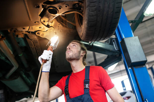 istock Attentive repairman standing under raised car 1291621584
