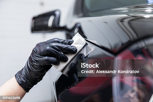 istock The process of applying a nano-ceramic coating on the car's fender by a male worker with a sponge and special chemical composition to protect the paint on the body from scratches, chips and damage. 1291622698