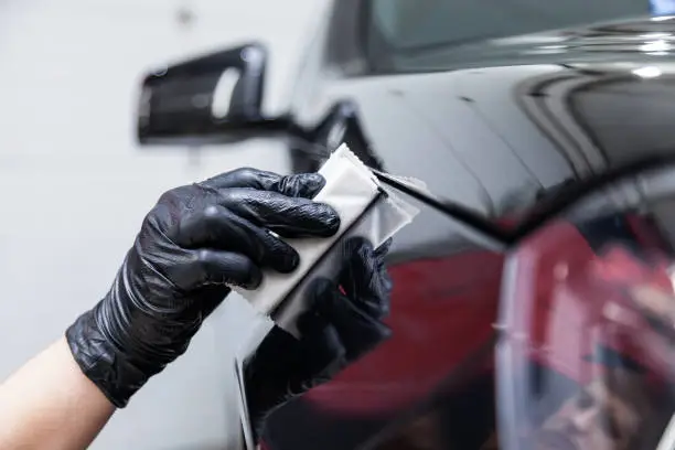 Photo of The process of applying a nano-ceramic coating on the car's fender by a male worker with a sponge and special chemical composition to protect the paint on the body from scratches, chips and damage.
