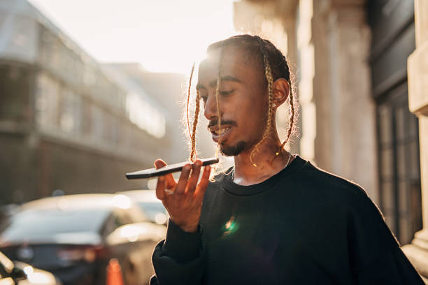 Rapper using smart phone for voice messaging outdoors in the city