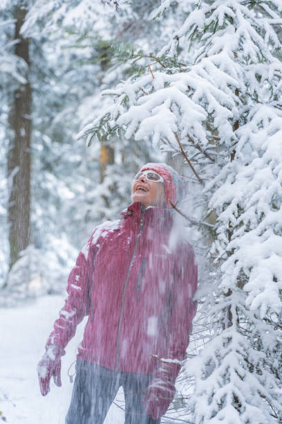istock ageless senior woman in winter forest, standing under falling snow 1291623054