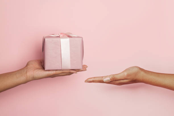 istock Hand holding gift on pastel pink 1291625897