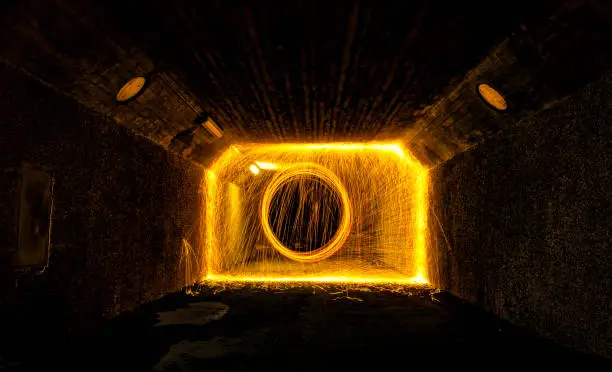 Burning steel wool being used to create beautiful imagery, photographed in a narrow passage, tunnel