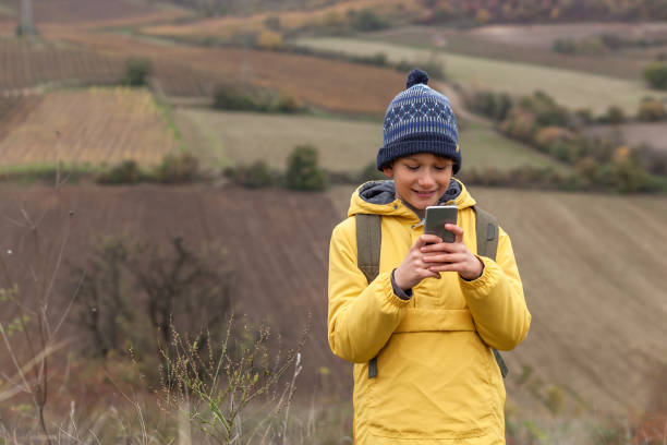 自然の中でスマートフォン上の幸せな小さな男の子のテキストメッセージ。 - child text messaging little boys male ストックフォトと画像