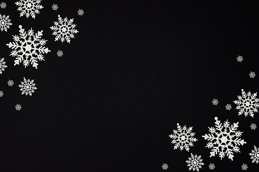Winter composition made of snowflakes on black background with copy space, Christmas card, flat lay, top view.