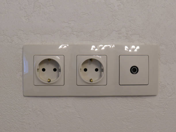 istock Electrical power outlets and switches in a white plastic frame on the wall close-up 1291631871
