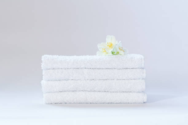 istock Four white neatly folded terry towels with a jasmine flower on a light background 1291632861