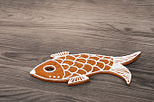 Sweet fish baked from Christmas gingerbread cookie on a wood background