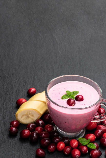 rosa smoothie mit preiselbeere und banane in glastasse auf schwarzem stein hintergrund - healthy lifestyle cranberry healthy eating milk shake stock-fotos und bilder