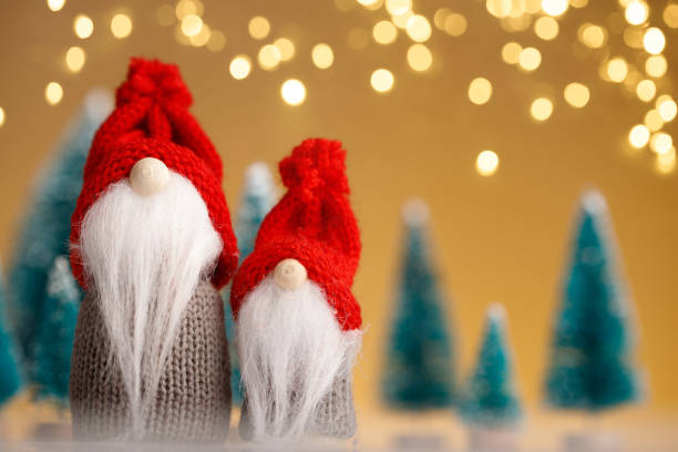 istock Two Christmas gnomes in red hats on a gold background 1291633934