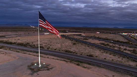 Aerial ahot of a US flag waving over a freeway at a truck stop near Salome in Arizona.