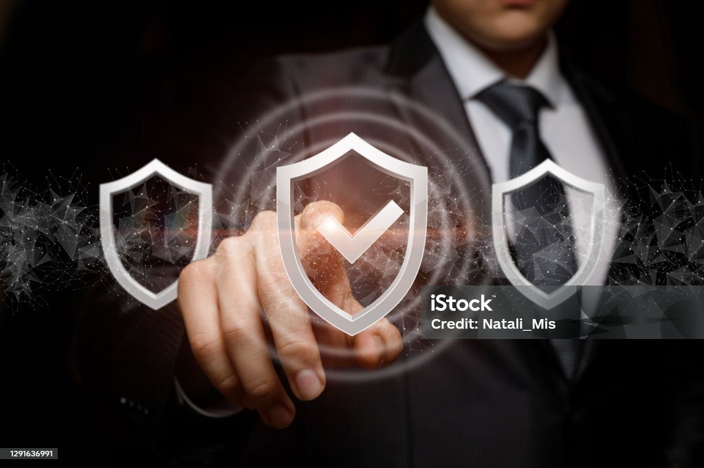 Businessman exposes the selected system protection . Businessman exposes the selected system protection on a dark background. Check Mark Stock Photo
