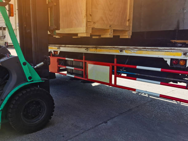 istock Worker driving forklift loading shipment carton boxes goods on wooden pallet at loading dock from container truck to warehouse cargo storage in freight logistics, transportation industrial, delivery 1291637109