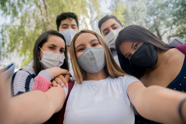 istock Group of students wearing facemasks at school and taking a selfie 1291638056