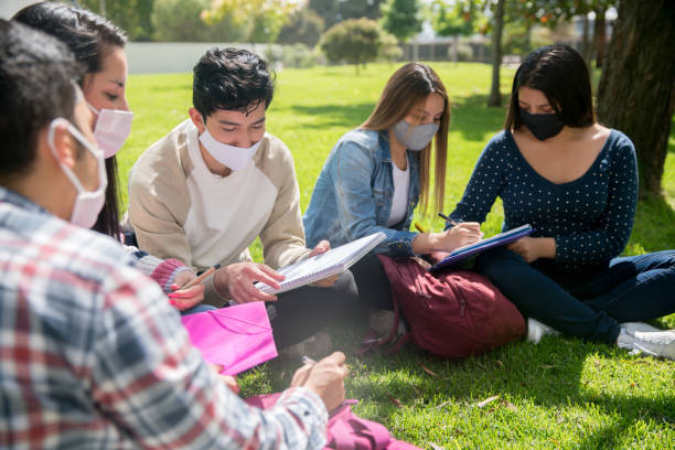 istock Group of students wearing facemasks at the school campus while studying outdoors 1291638070