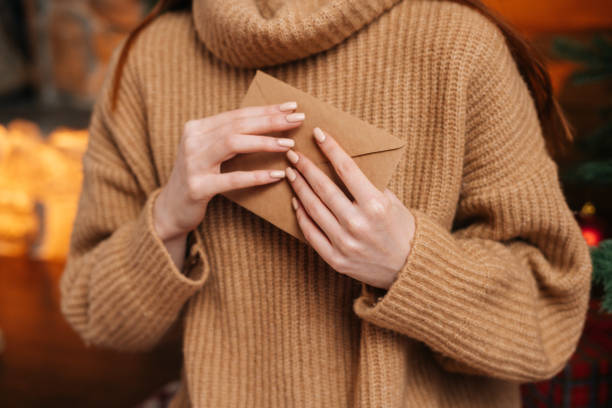 visão de perto de jovem irreconhecível vestindo suéter de inverno segurando em mãos envelope de papel - christmas santa claus gift invitation - fotografias e filmes do acervo