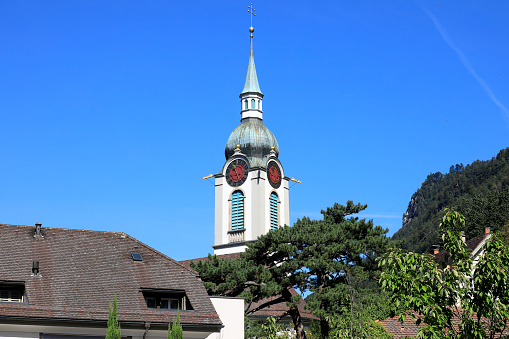 Altdorf, Switzerland - August 27, 2020: Church tower and spire seen against the blue sky. This tower is part of the church in Altdorf, the capital of the Swiss canton of Uri. This is one of the countless wonderful places in Switzerland, which is a tourist attraction often visited by many tourists from all over the world.