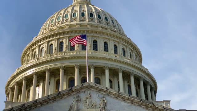 A close up of the United States Capitol dome and the waving US national flag