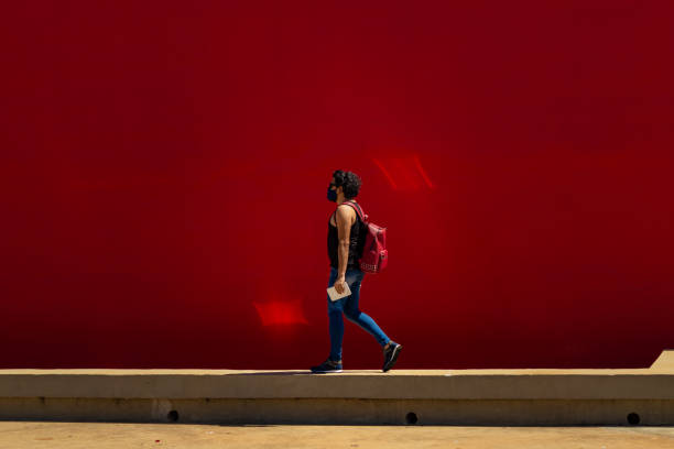istock Man in mask and backpack walking with a red wall in the background. 1291646451