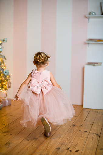 Full length rear view of little girl in beautiful pink dress with tied bow at the belt