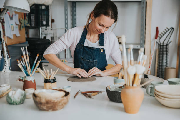 young artisan woman working with her hand a piece of ceramic focus on person stock photo