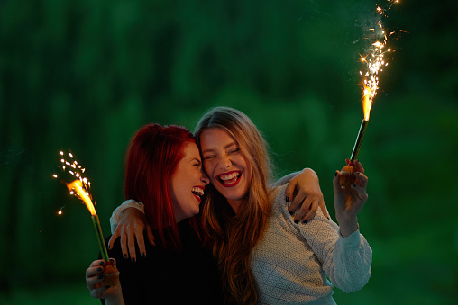 New Year's eve laughters of two women, blond and redhead, outdoors in garden