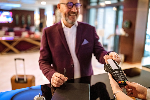 Senior businessman checking out from hotel, contactless paying method