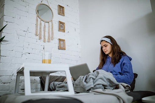 Women using laptop in early morning, working from her bedroom