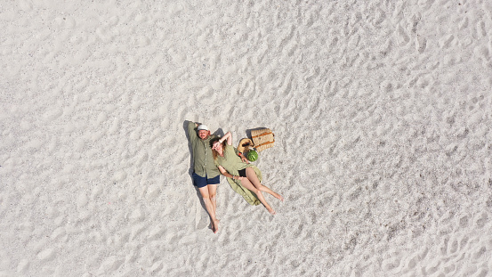 Aerial view of a young couple lying on the white sand. man and woman spend time together and travel through the desert.