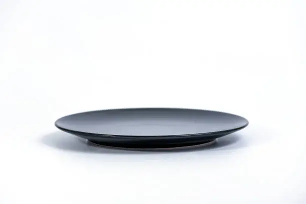 Empty Black plate isolated on white background side view, selective focus