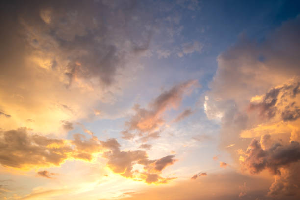 istock Dramatic cloudy sunset landscape with puffy clouds lit by orange setting sun and blue sky. 1291674484