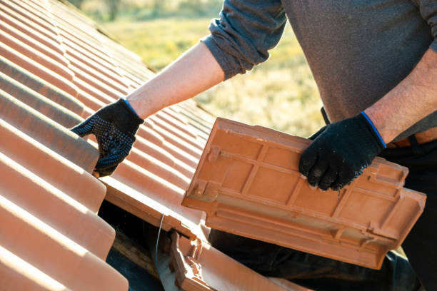 建設中の住宅用建物の屋根を覆う木製のボードに取り付けられた黄色のセラミック屋根瓦をインストールする労働者の手のクローズアップ。 - roof tile ストックフォトと画像