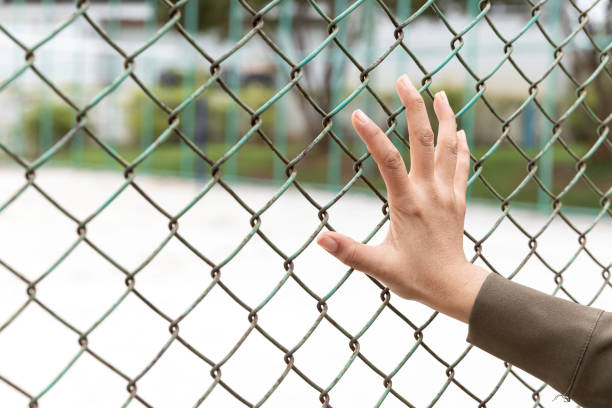 istock Hand hold steel wire fence net. hope emotion. 1291677937