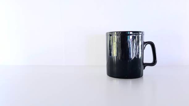 istock Black ceramic mug is placed on a desk in a white room, 1291678852