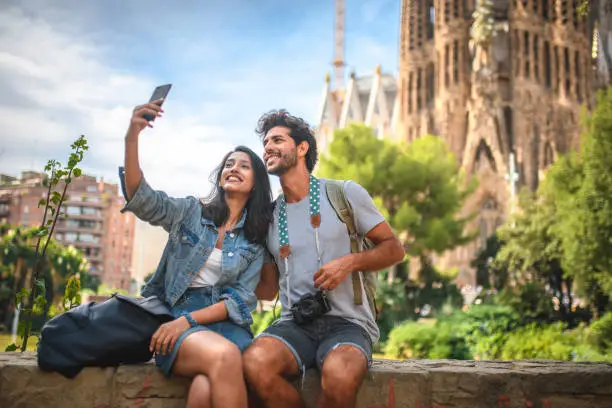 Photo of Young Couple Taking Break from Sightseeing for Selfie