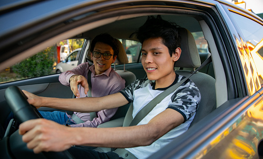 Two young men in a driving session. The instructor is teaching the young man to drive
