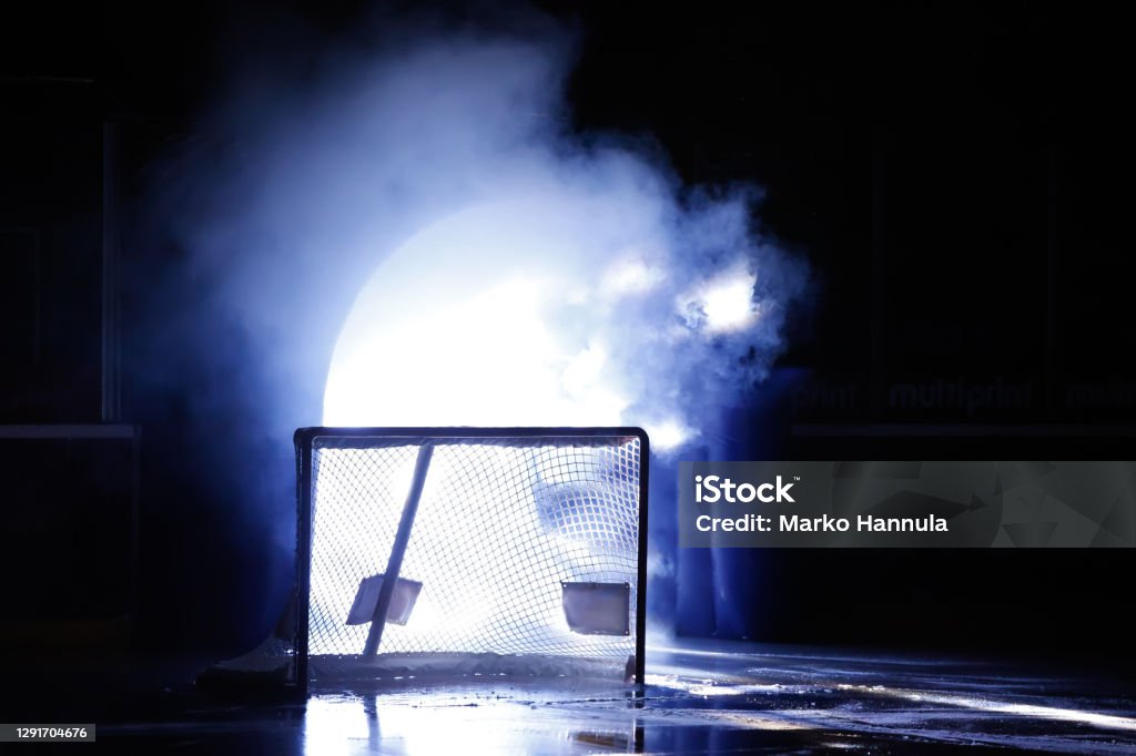A silhouette of an ice hockey goal in front of illuminated player entrance. Ice Hockey Rink Stock Photo