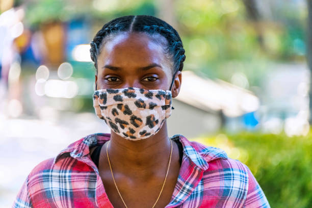istock Young black female college student posing wearing a protective face mask 1291704991