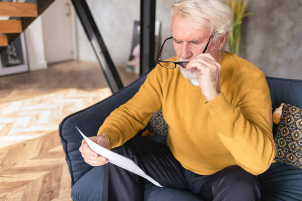 Senior man reads document from bank about credit debt. Financial crisis concept. Senior man reads document from bank about credit debt. Financial crisis concept reading glasses stock pictures, royalty-free photos & images