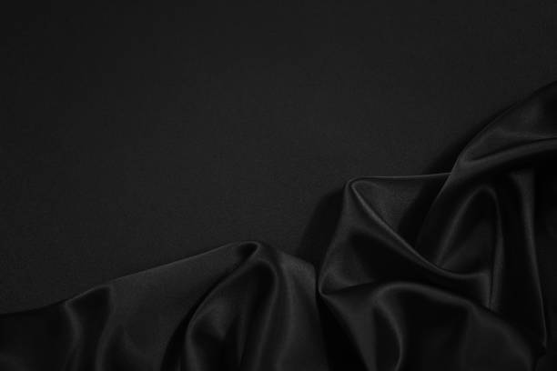 istock Black silk satin fabric background. Copy space for your design. Delicate wavy folds. Beautiful elegant black background. 1291709361