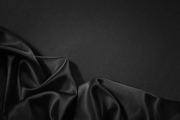 istock Black silk satin fabric background. Copy space for your design. Delicate wavy folds. Beautiful elegant black background. 1291714285