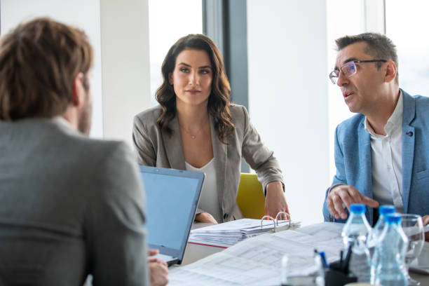 istock Businessman explaining the project on sheet in front of him to colleagues 1291716143