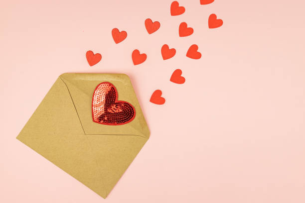 istock Paper craft envelope with scattering red hearts on pink background. With copy space. Creative layout for St Valentines Day. 1291716874